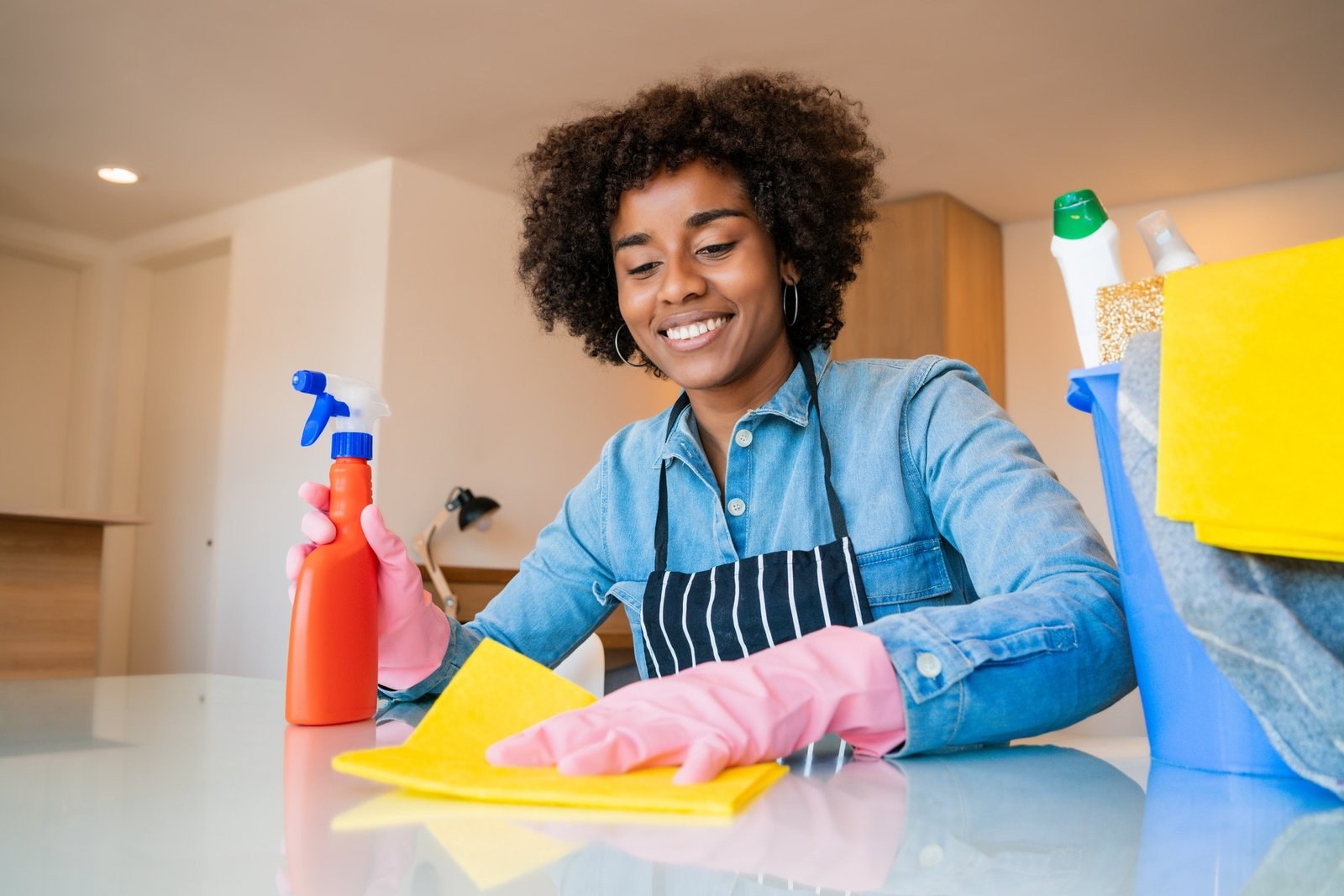 Woman cleaning a home with gloves and a spray bottle