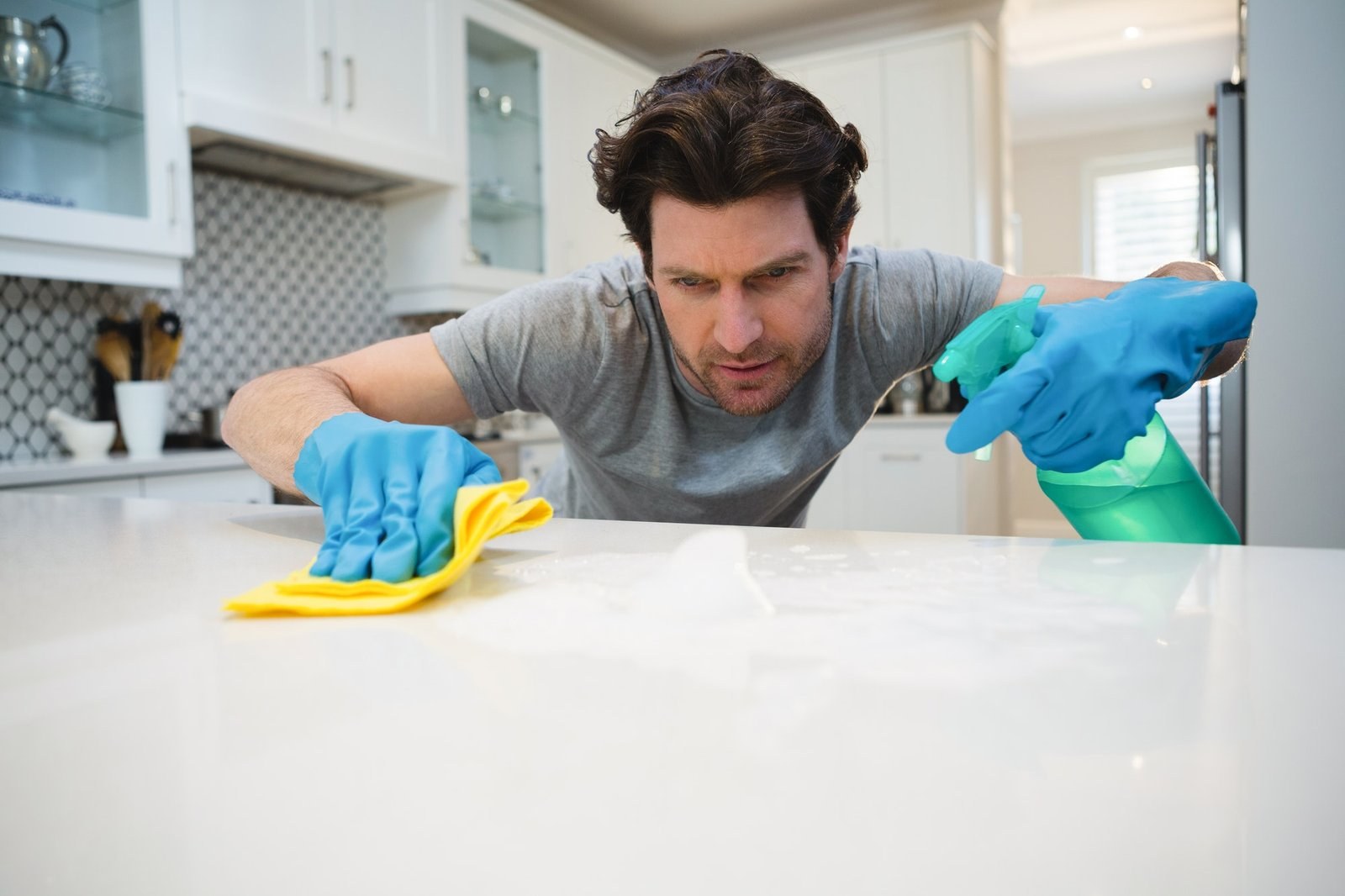Man cleaning a kitchen worktop at home